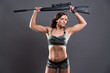 © ysbrandcosijn - Muscled fitness army girl holding gun. Studio shot against grey.