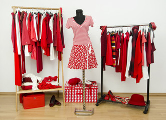 Dressing closet with red and white clothes arranged on hangers.