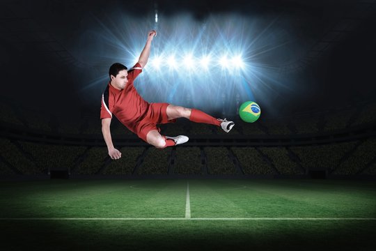 Fit football player jumping and kicking
