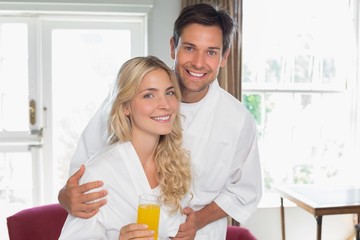 Wall Mural - Young couple with orange glass at home