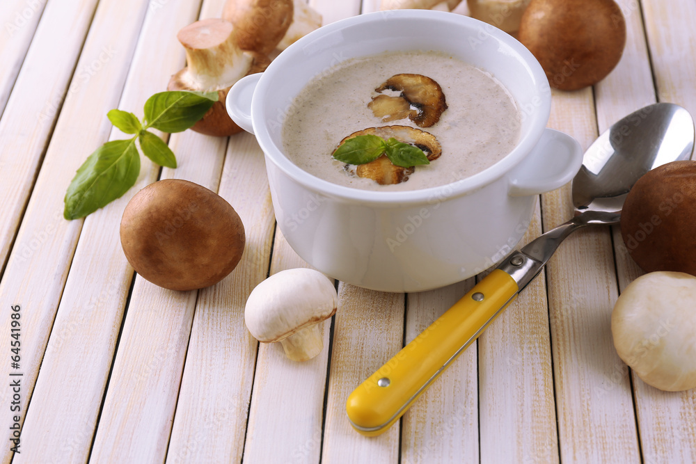 Mushroom soup in white pot on wooden background