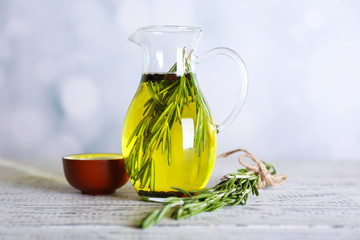 Wall Mural - Essential Oil with rosemary in glass jug, on light background