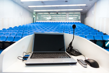 Laptop on the rostrum in conference hall.