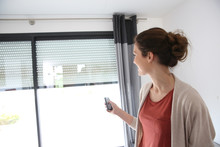 Woman Using Remote Control To Open Electric Shutter