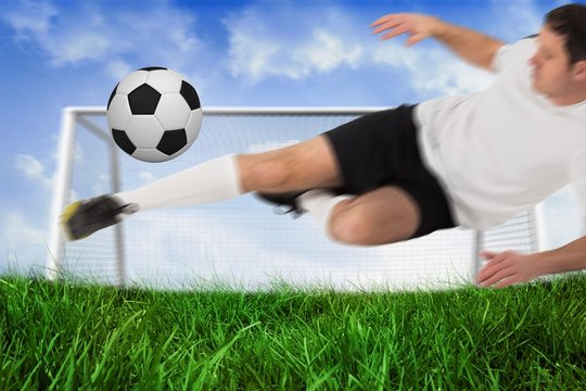 Football player in white kicking ball