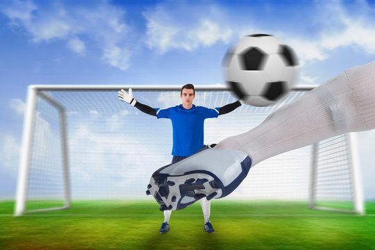 Football player striking ball at goalkeeper