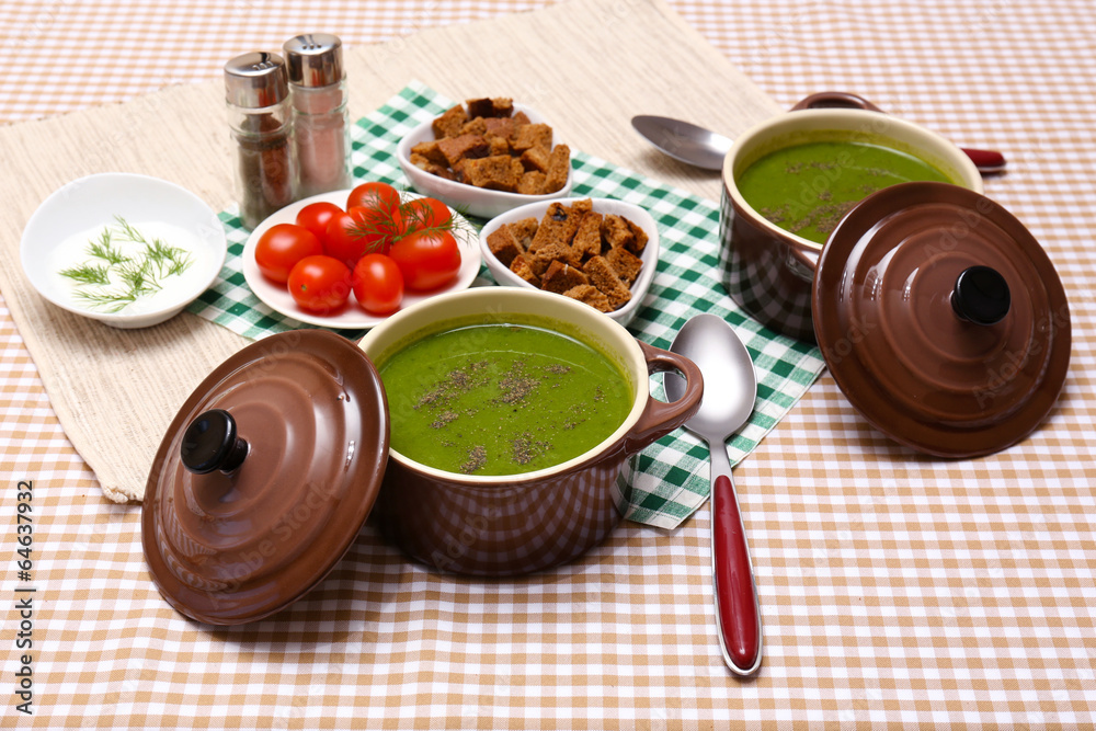 Tasty soup in saucepans on tablecloth, close up
