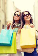 Poster - two girls in sunglasses with shopping bags in ctiy