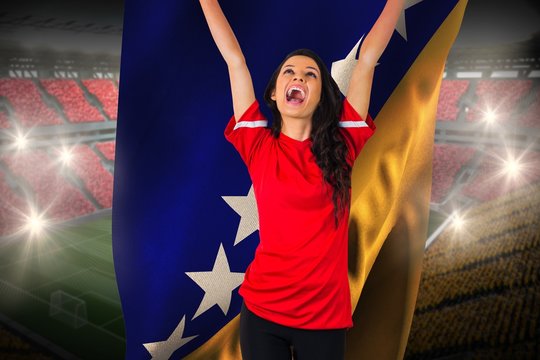 Cheering football fan in red holding bosnia flag