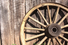 Wooden Wheel Leaning Against Barn