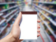 white blank notebook in woman hand and supermarket background