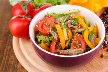  Beef salad in bowl with vegetables and spices on wooden table
