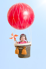 cheerful kid on hot air balloon in the sky