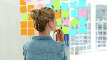 Wall Mural - Blonde designer looking at post its on window