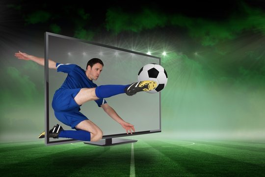 Fit football player kicking ball through tv
