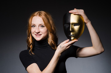 Redhead woman iwith mask in hypocrisy consept against grey backg