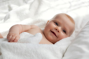 Newborn baby girl wrapped in a fluffy towel, smiling