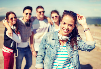 Wall Mural - teenage girl with headphones and friends outside