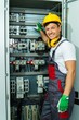 Cheerful electrician in a safety hat on a factory