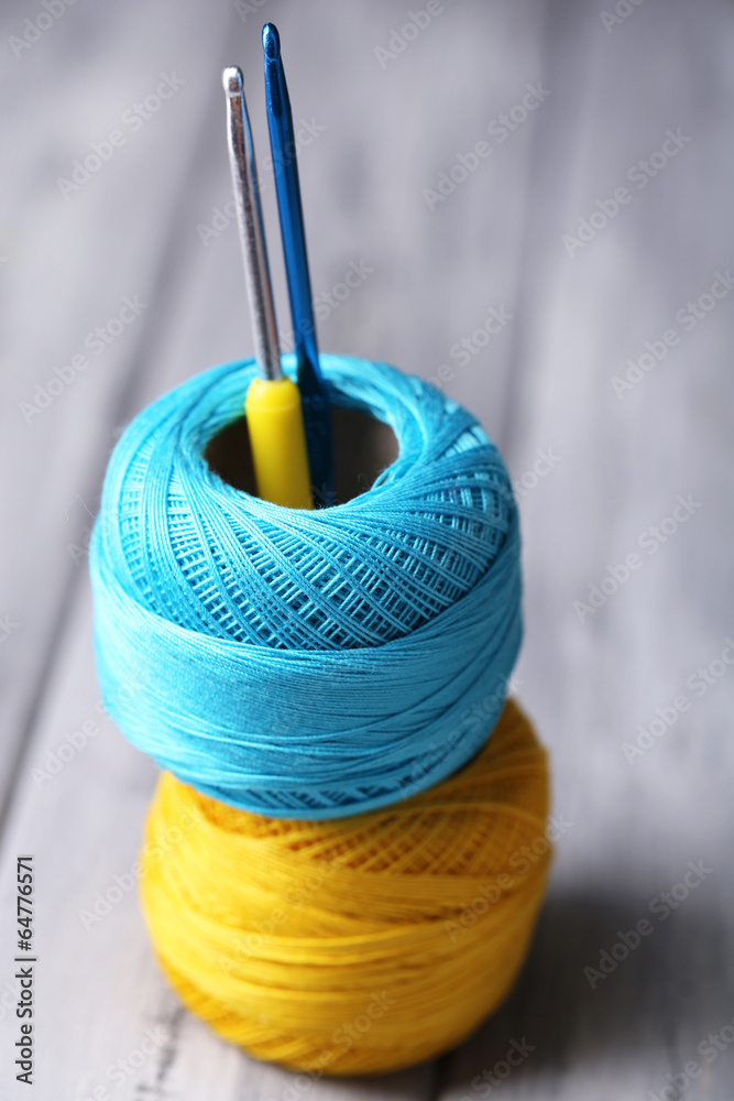 Colorful clews and crochet hook on wooden background