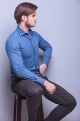 Sticker - side view of a young fashion man sitting