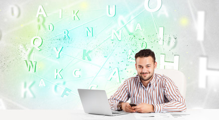 Business man at desk with green word cloud