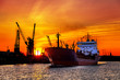 Silhouette of sea port cranes over sunset