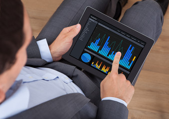 Poster - Businessman Analyzing Graphs On Digital Tablet