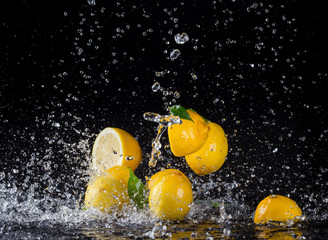 Lemons in water splash on black background