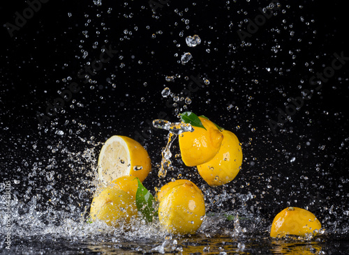 Fototapeta na wymiar Lemons in water splash on black background