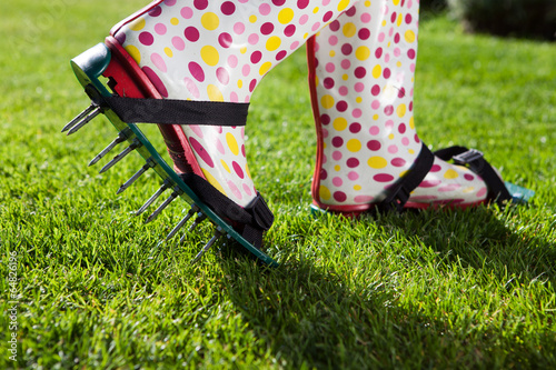 Fotografia, Obraz Woman wearing spiked lawn revitalizing aerating shoes