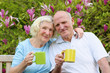 © cromary - Happy loving senior couple drinking tea from big colorful mugs