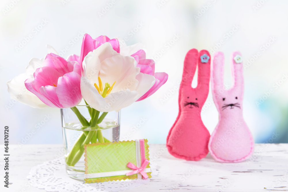 Beautiful tulips in bucket in vase on table on light background
