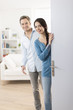 © jackfrog - Cheerful couple inviting people to enter in home