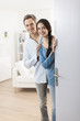© jackfrog - Cheerful couple inviting people to enter in home