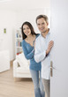 © jackfrog - Cheerful couple inviting people to enter in home
