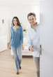 © jackfrog - Cheerful couple inviting people to enter in home