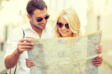 Canvas Print - smiling couple in sunglasses with map in the city