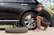 © kolotype - Young man changing the punctured tyre on his car