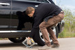 © kolotype - Man placing a hydraulic jack under his car