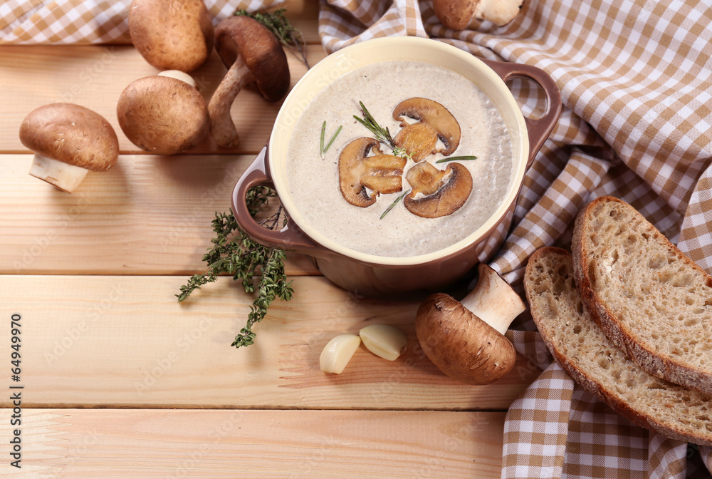Mushroom soup in pot, on napkin,  on wooden background