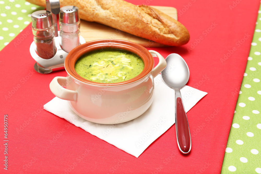 Tasty soup in saucepan on tablecloth, close up