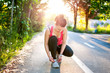 © aboutmomentsimages - Portrait of active joggin woman resting and preparing shoes