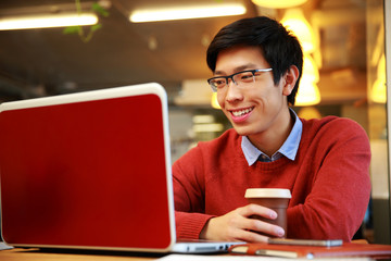 Wall Mural - Happy asian man in glasses working on laptop