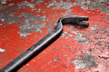An Old Crowbar On A Red Background