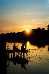 two fisherman silhouette against sunset