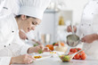 © jackfrog - closeup on a  female chef preparing a dish her team in the backg