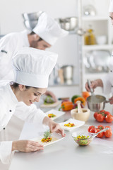  female chef preparing a dish her team in the background