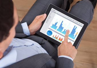 Poster - Businessman Comparing Graphs On Digital Tablet