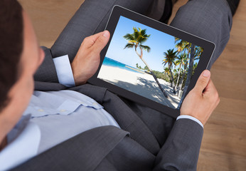 Poster - Businessman Looking At Beach Photo On Tablet In Office